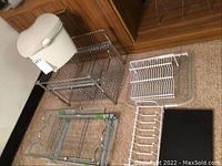 Wide shot showing two metal frames, countertop compost bin, and additional wire racks on carpeted floor.