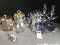 Photo of the assortment showing ice buckets, pitcher, various glasses, and corkscrew on surface