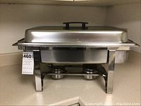Metal chafing dish set displayed on countertop showing side angle, reveals stand and two fuel holders underneath