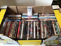 Box with over 60 assorted DVDs in their cases, standing upright in corrugated cardboard box