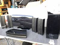 Samsung home theatre speaker system laid out on table showing subwoofer, center speaker, and satellite speakers