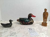 Photo showing three items: black ceramic duck, Herb Faucher painted soapstone duck, and A. Thibault wooden fisherman figurine standing.