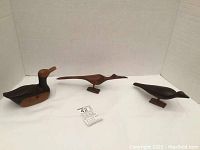 Three hand carved wooden birds displayed together, showing size and shape differences.