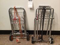 Two metal luggage trollies side by side, one with orange bungee cord the other with black bungee cord.
