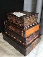 Stacked view of four hand-carved wooden boxes showing intricate patterns and varying wood tones.