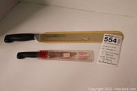 Two knives in original protective sheaths, one yellow 10" sheath and one clear 3" sheath, on white background