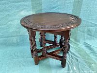 Round solid oak gateleg table with carved edge detail and turned legs shown from front angle.