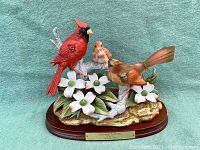 Full view of porcelain cardinal family figurine including male, female, and baby cardinals perched on branch with flowers and leaves, mounted on wooden base with brass plaque.
