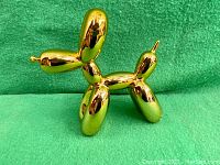 Front-left angled view of gold balloon dog against green background