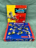 Photo of Junior Engineer and Meccano Erector building set boxes stacked, showing front box artwork and design.
