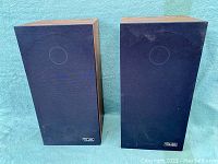 Two rectangular Audio Research speakers with wood sides and black fabric front covers with circular impressions. Both speakers show some wear on the fabric material.