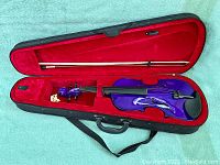 Purple wood Mendini violin inside black case with red velvet lining, includes bow secured in case.