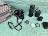 Overview of main items with camera, lenses, bag, lens caps, filters, and accessories on green background.
