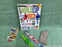 Full view of two Swatch 2014 World Cup watches, multiple replaceable flag strap holders, and souvenir magazine
