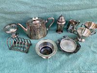 Full view of the antique silverplate tea set and accessories arranged on a fabric backdrop.