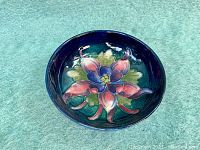 Top down view showing detailed multicolor floral design against a dark blue background inside the bowl.