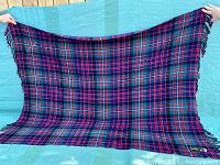 Full view of the vintage tartan wool blanket displayed being held open showing full design and fringe edge details.