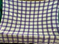 Full view of blanket showing purple and cream checkered wool pattern
