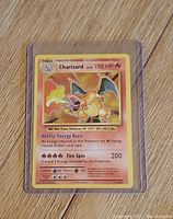 Photo of Charizard Pokemon card in protective sleeve showing front details including abilities and attack damage
