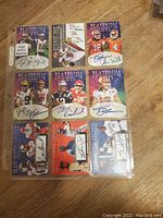 Top view of nine Platinum Cuts football cards with player images and signatures on a wooden surface