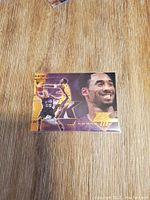Basketball trading card showing Kobe Bryant with a close-up smile and action shot basketball image, purple and gold Lakers colors