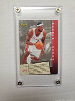 Front image of LeBron James basketball rookie debut card in a clear protective case showing player dribbling in Cavaliers uniform.