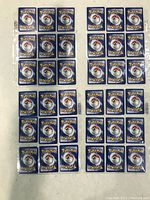 Backs of multiple Pokémon cards showing the classic blue back design with Poké Balls, arranged in rows inside protective sleeves.