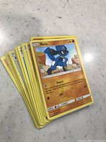 Stack of yellow-bordered Pokemon cards with Riolu card on the top, showing attack moves Detect and Jab, hit points 70.