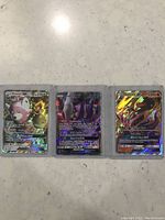 Front view of three holographic Pokémon cards featuring Bewear GX, Mewtwo GX, and Salamence GX, in protective sleeves.