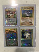 Four near mint Japanese Edition Pokémon cards arrayed in protective sleeves, featuring two Trainer cards and two Pokémon cards with holographic effects and Japanese text.
