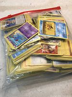 Top view showing multiple Pokémon cards with yellow borders inside a clear plastic bag.