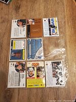 Eight Wayne Gretzky hockey trading cards displayed face and back in a plastic sleeve on wood surface.