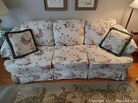 Front view of the ivory floral sofa with matching cushions showing fabric pattern and condition.
