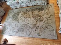 Full view of 5x8 floral area rug on hardwood floor, shows overall design and condition.