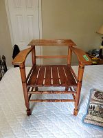 Full front view of the solid wood chair showing slat seat and wooden arms.