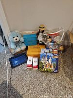 Lot on floor showing teddy bear, Anne doll, Trivial Pursuit box, puzzles, books, and toys