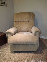 Front view of beige patterned La-Z-Boy rocker recliner with cushioned armrests and segmented back.
