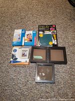 Assortment of digital photo and craft items including HP photo paper packs, digital photo brag book, IKEA shadow boxes, and flower press kit.