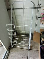 Front view of the white wire folding shopping cart showing the wire basket, wheels, and metal frame.