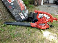 Full view of red Toro UltraPlus blower vac next to its accessories and packaging box outdoors on grass.