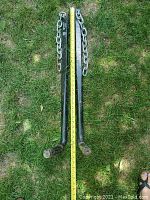 Pair of trailer stabilizer bars laying on grass with a measuring tape showing approximately 29 inches in length.