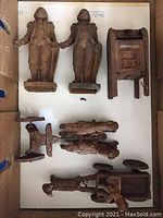Top-down view showing two cast iron figure banks, a chair-shaped bank item, and smaller cast iron items, all heavily rusted as is.