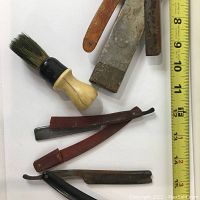 Top view showing shaving brush and four straight razors, two with broken handles, rust visible on blades