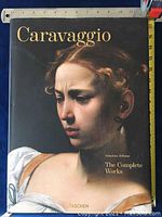 Front cover of the large hardcover book titled 'Caravaggio: The Complete Works' published by Taschen featuring a painting of a woman's face.