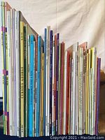 Side view of children’s books collection showing colorful spines of varying sizes and thicknesses, including multiple Curious George titles and other assorted books.