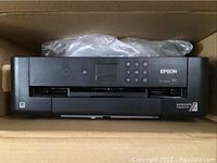 Front view of Epson XP-1500 printer inside box showing control panel and branding