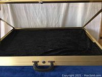 Closed glass display case showing metal frame and handle on blue surface.