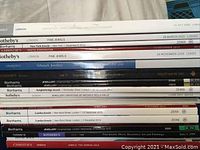 Stack of multiple Sotheby's, Christie's, Bonhams, and Lempertz auction catalogs for jewelry sales in various years and cities.