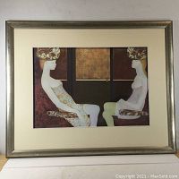 Full view of the framed lithograph showing two seated female figures in surreal style with elaborate headpieces.