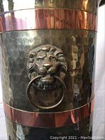 Close-up of lion head feature on the brass and copper holder, showing detailed face and attached ring.